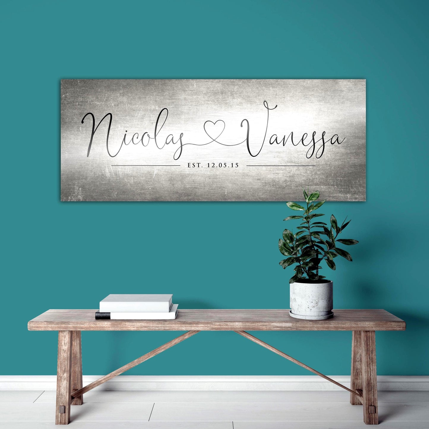 Unique Anniversary gifts like Honeycomb Proverbs' Personalized Heart Name signs are popular for ten year wedding anniversaries. One of their tarnished metal Heart Name sign hangs above a bench with a potted plant. The sign is extra large sized and features personalized names connected by a heart in a whimsical calligraphy font. The couple's established date sits beneath their names to mark their special day.